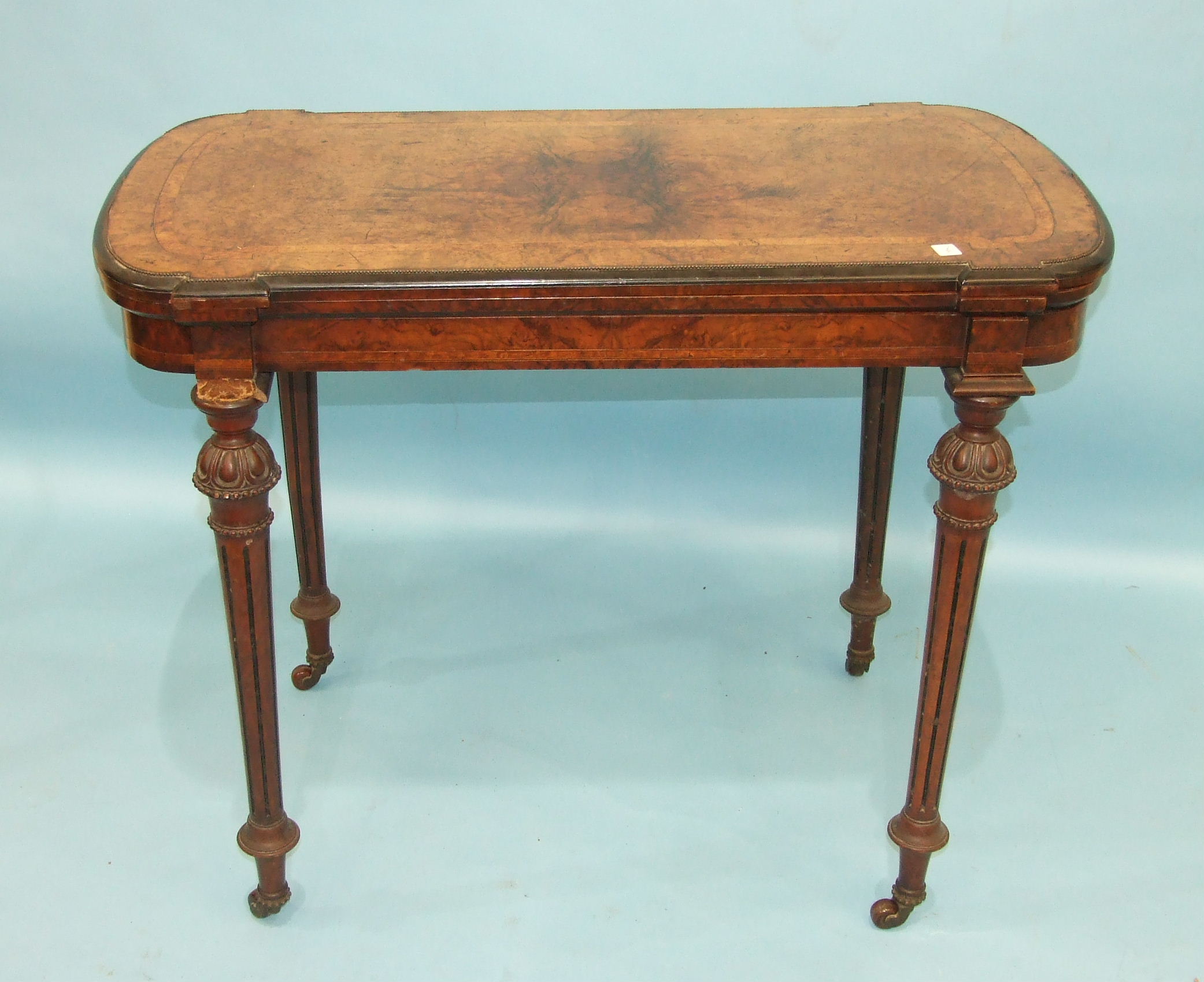 A Victorian burr walnut card table, the fold-over top with metal beaded border raised on carved