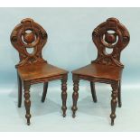 A pair of mahogany hall chairs with pierced backs and shaped solid seats, on turned front legs, (