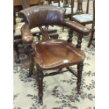 An early-19th century mahogany library chair, the open curved back and padded arms on carved