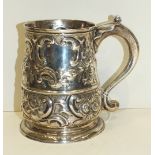 A George III baluster tankard with scroll handle and embossed floral and foliate decoration,