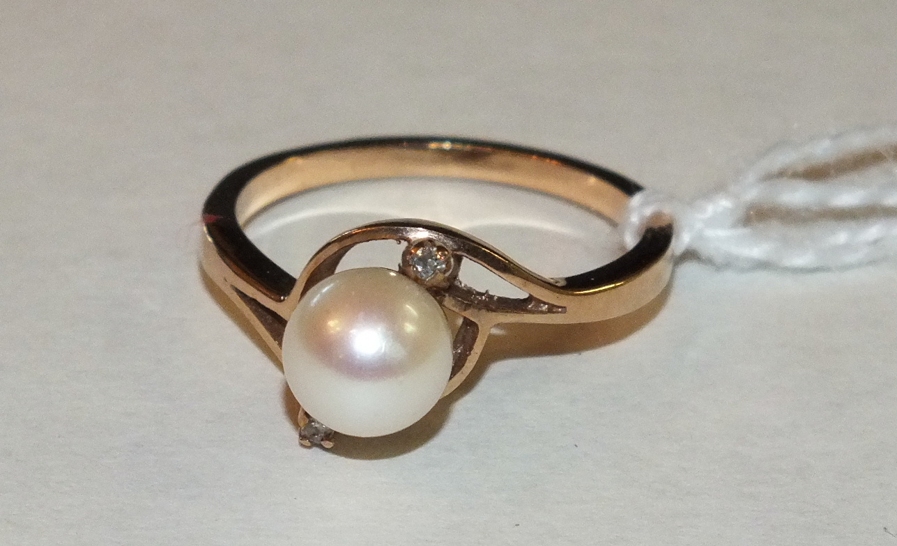 A gold cross-over ring set a cultured pearl between two diamond points, size M, 2.8g.