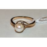 A gold cross-over ring set a cultured pearl between two diamond points, size M, 2.8g.