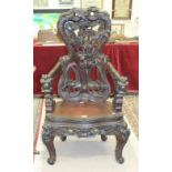 A carved hardwood armchair in the Oriental taste flamboyantly-pierced and carved with flowers and