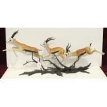 American, 20th century, a trio of finely-detailed porcelain gazelles bounding through a bronze