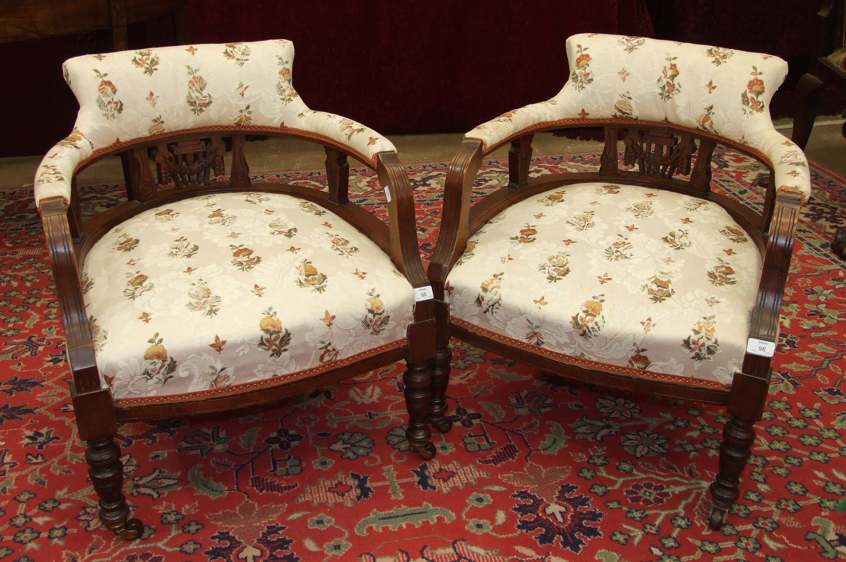 A pair of Edwardian walnut-framed low armchairs, each with upholstered back, arms and seats, on