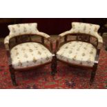 A pair of Edwardian walnut-framed low armchairs, each with upholstered back, arms and seats, on