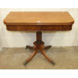 An early-19th century mahogany tea table, the fold-over top on carved column and hipped sabre legs