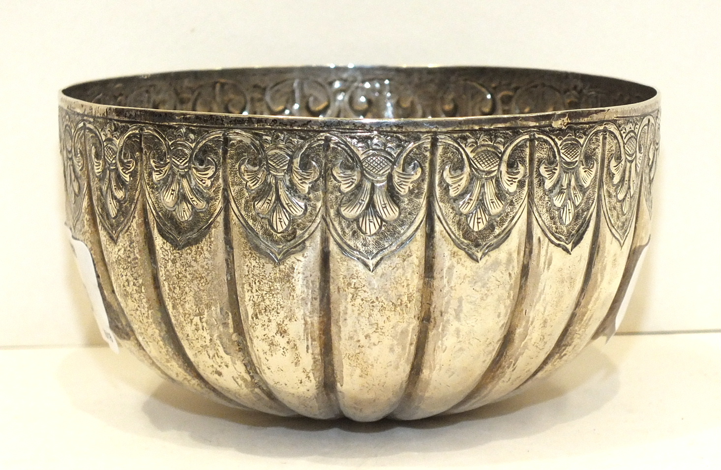 A circular white metal bowl of ribbed form, having embossed decoration, 10.7cm diameter, 5.5cm