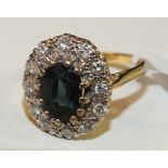 A sapphire and diamond cluster ring claw-set a sapphire within a border of twelve brilliant-cut