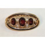 A modern 9ct gold oval brooch set three garnets, in open scrolling mount, 5.6g.