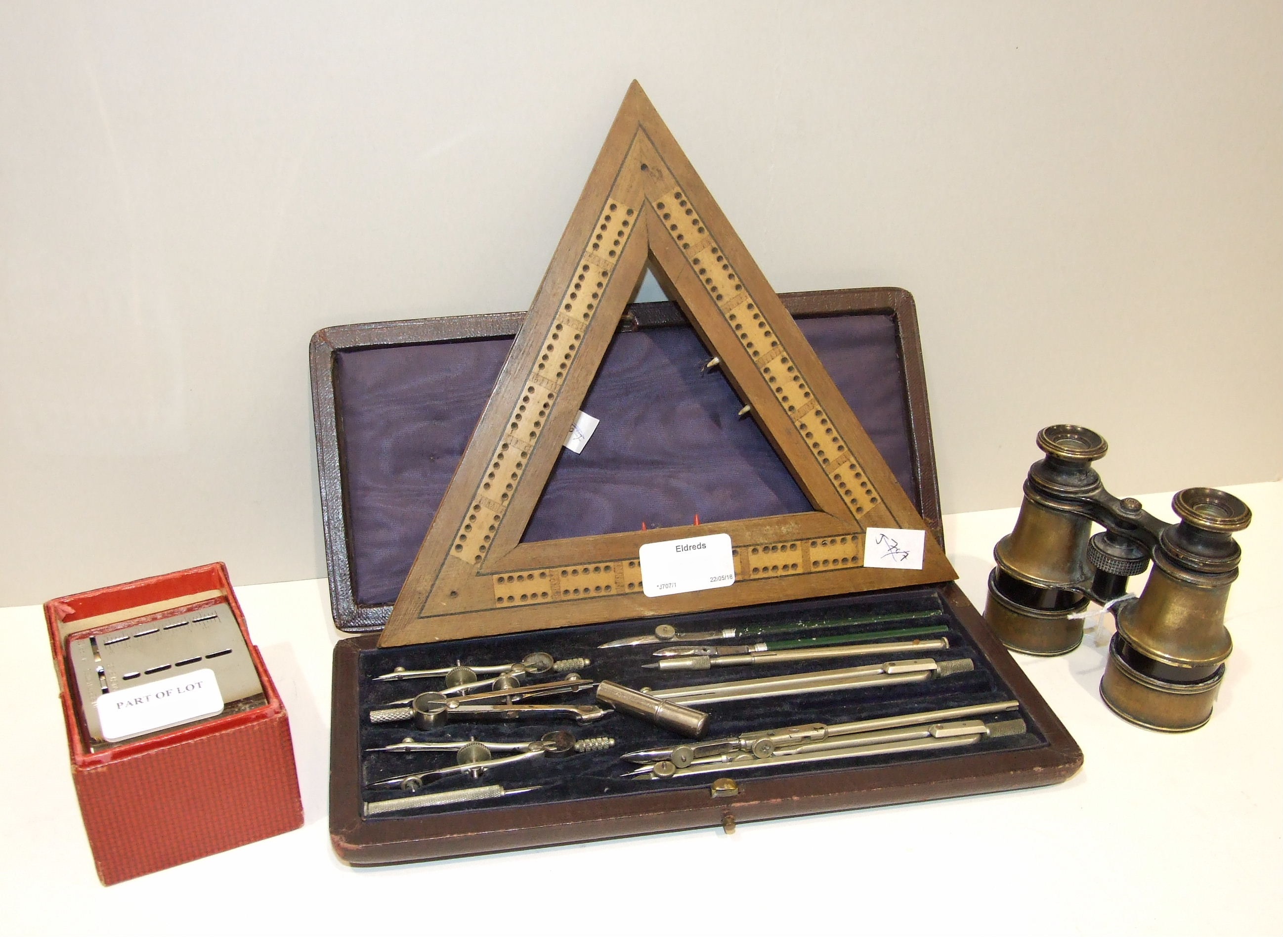 A wooden triangular Euchre board, 24cm, a small pair of binoculars, a case of drawing instruments