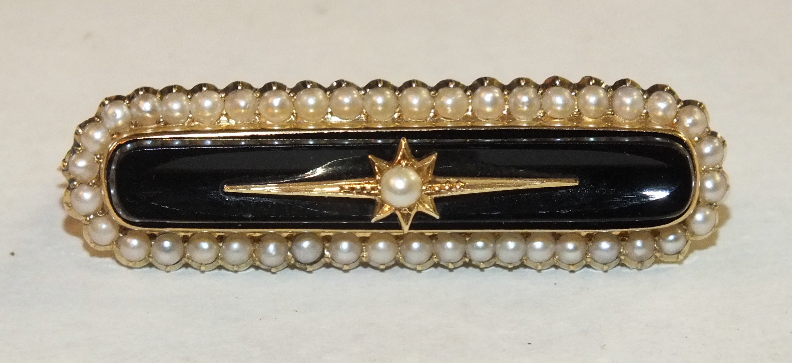 A Victorian onyx and pearl-set mourning brooch in 15ct gold mount, with locket back, 4cm long, 9g,