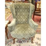 A Georgian-style mahogany wing armchair on carved cabriole front legs, with shell-carved feet and