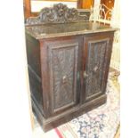 A Continental stained oak cupboard, the carved low back and rectangular top above a pair of carved