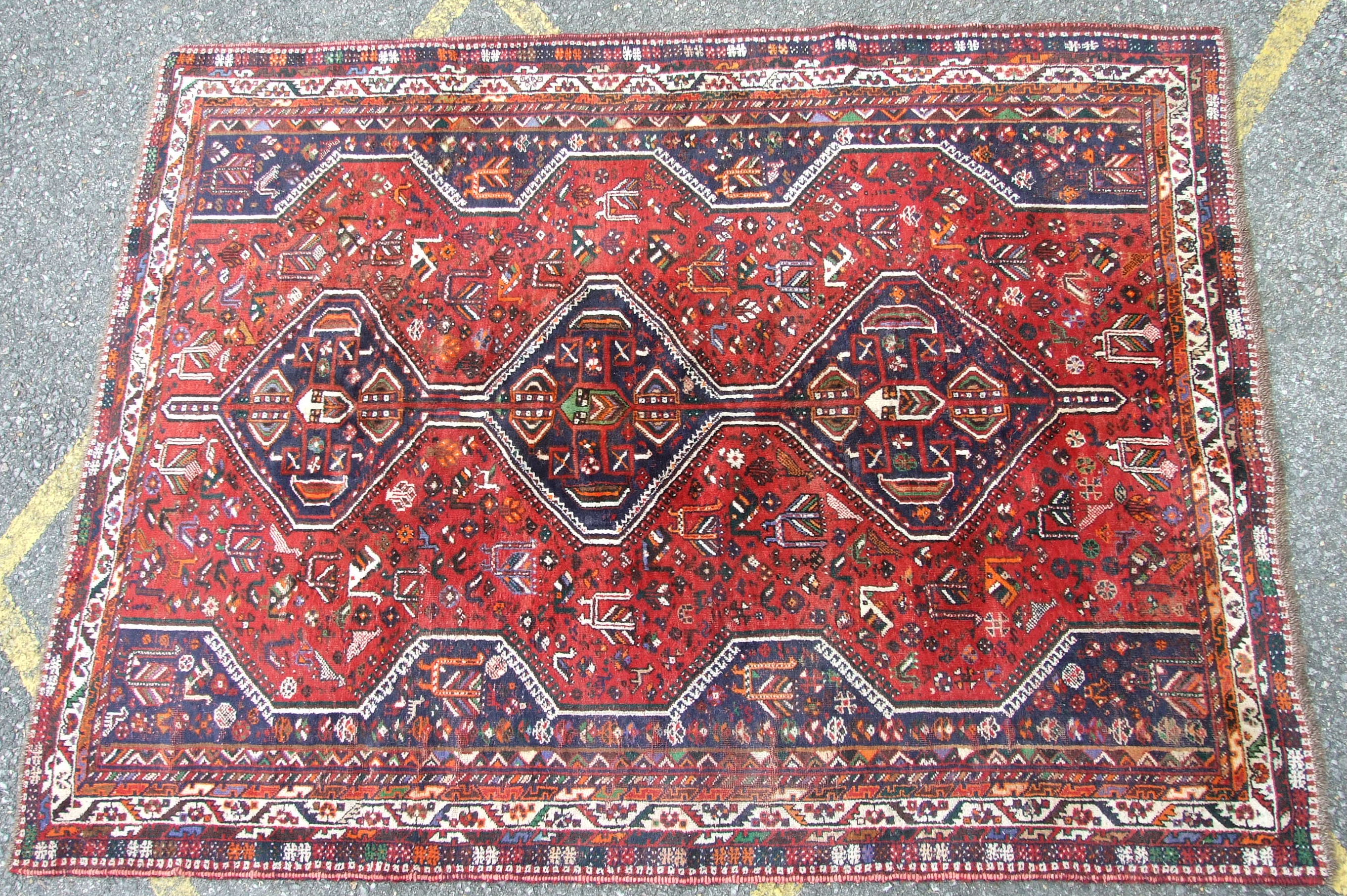 A Shiraz design wool carpet with triple pole medallion on crimson ground, 220 x 300cm, (some wear).