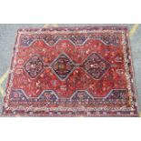 A Shiraz design wool carpet with triple pole medallion on crimson ground, 220 x 300cm, (some wear).