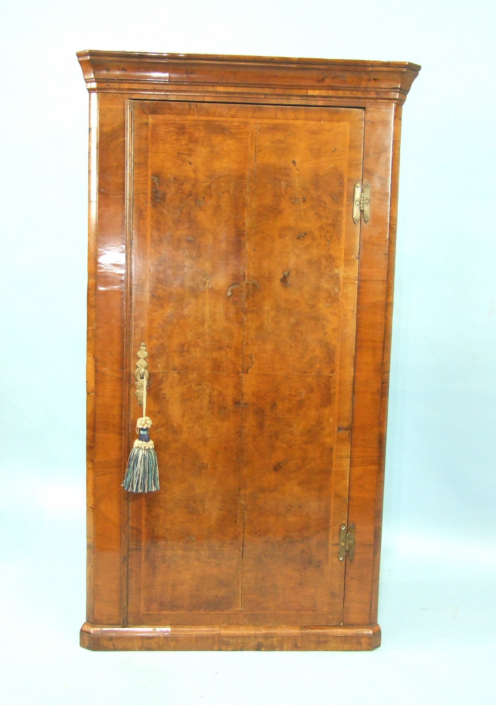 An 18th century walnut hanging corner cupboard, the moulded cornice above a single door enclosing