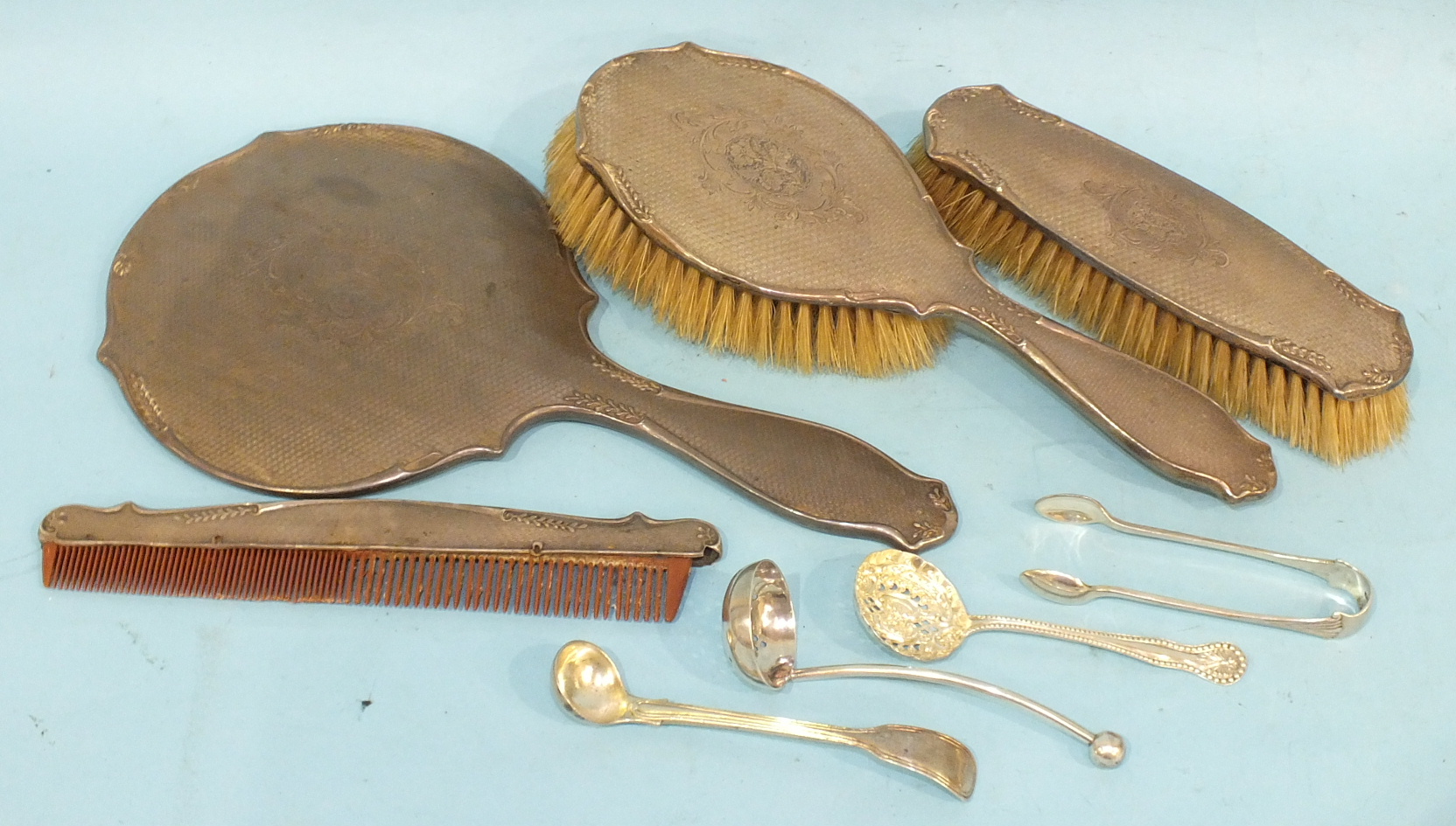 A silver four-piece dressing table set, comprising mirror, two brushes and a comb, with engine-