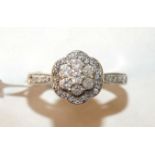 A diamond cluster ring claw-set seven brilliant-cut diamonds within a border of 8/8-cut diamond