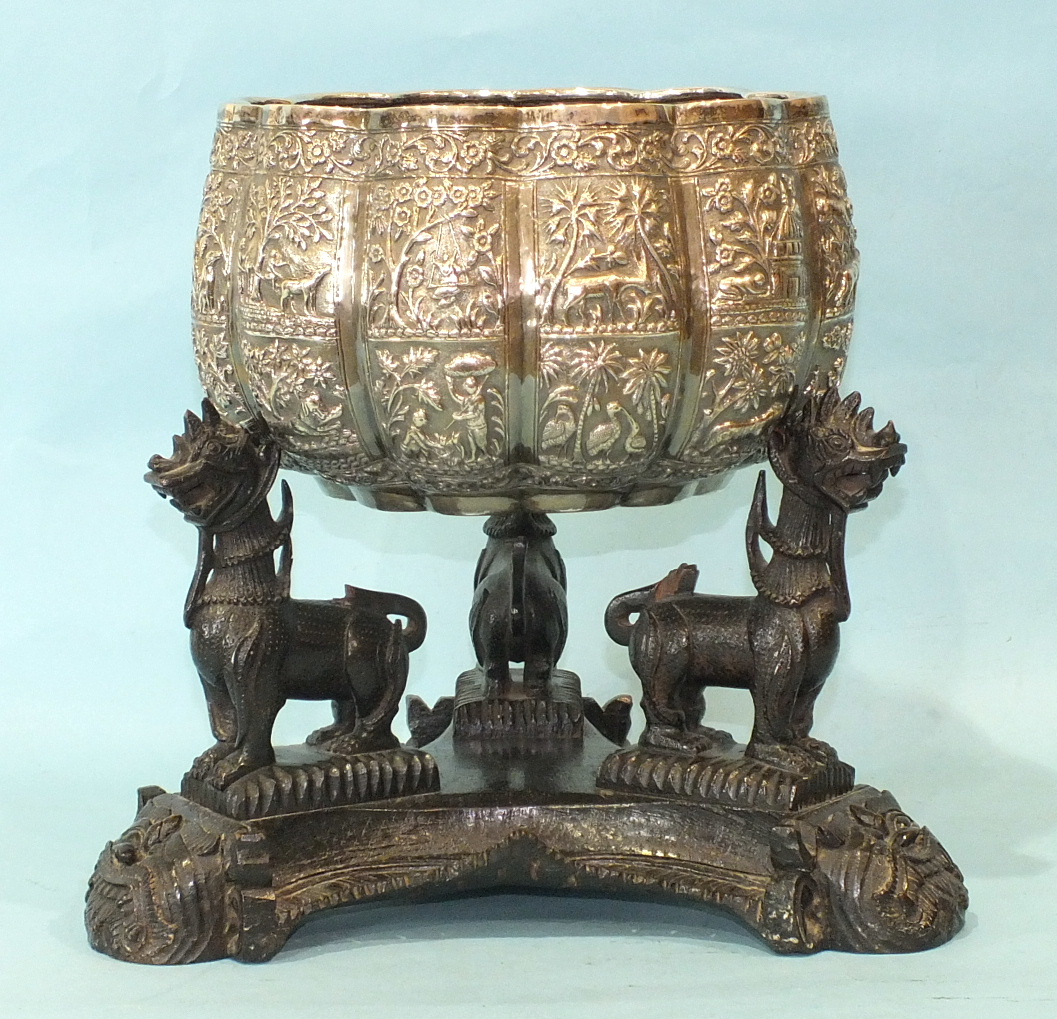 A large late 19th century Burmese white metal bowl of lobed form embossed with panels of figures,