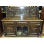 A 19th century Continental oak sideboard, the carved back panel depicting a siege above an