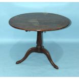 An 18th century yew wood tilt-top tripod table, the circular top supported on a turned column and