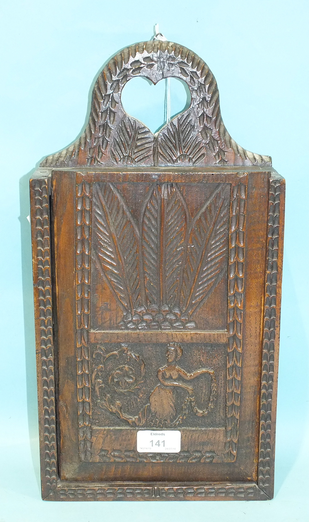 An antique carved fruit wood hanging candle box, the sliding door panel carved with a female