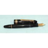 A Mont Blanc Meisterstück no.146 fountain pen with gold-coloured mounts on a black surface, the