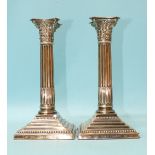 An Edwardian pair of silver Corinthian column candlesticks by Robert Pringle & Sons, on square