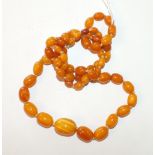 A string of sixty-one graduated yellow amber beads of ovoid shape, largest 24 x 15mm, 84cm long,