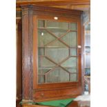 A Georgian oak and mahogany hanging corner cupboard, the dentil frieze above an astragal glazed door