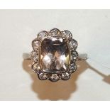 A morganite and diamond cluster ring collet-set a pale pink morganite within a border of twelve