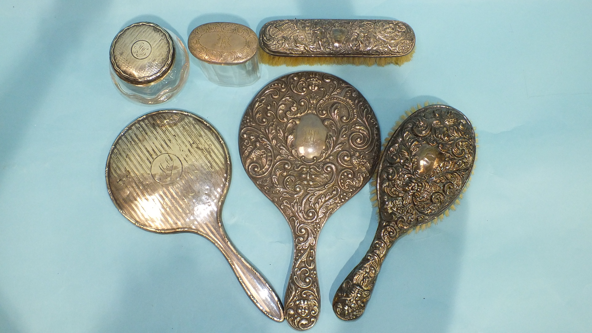 A silver-backed hand mirror with heavily-embossed bird, mask and floral decoration, Birmingham 1916,