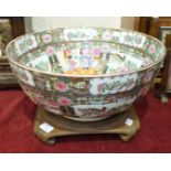 A reproduction Canton style porcelain punch bowl, 20cm high, on carved wood stand.
