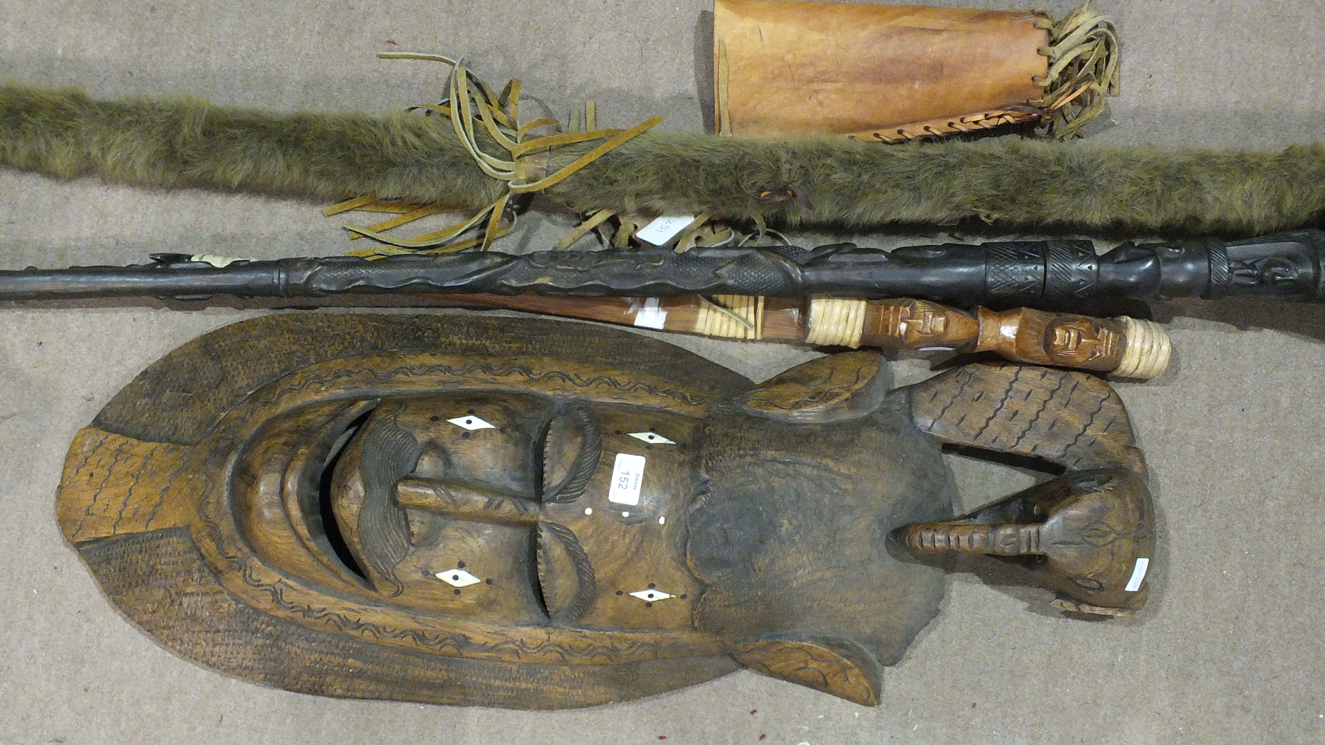 An African carved wood totem staff, 172cm long, a fur covered staff, 190cm long and a carved wood