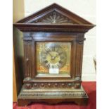 An Edwardian carved oak architectural form mantel clock with silvered chapter ring and gong-striking