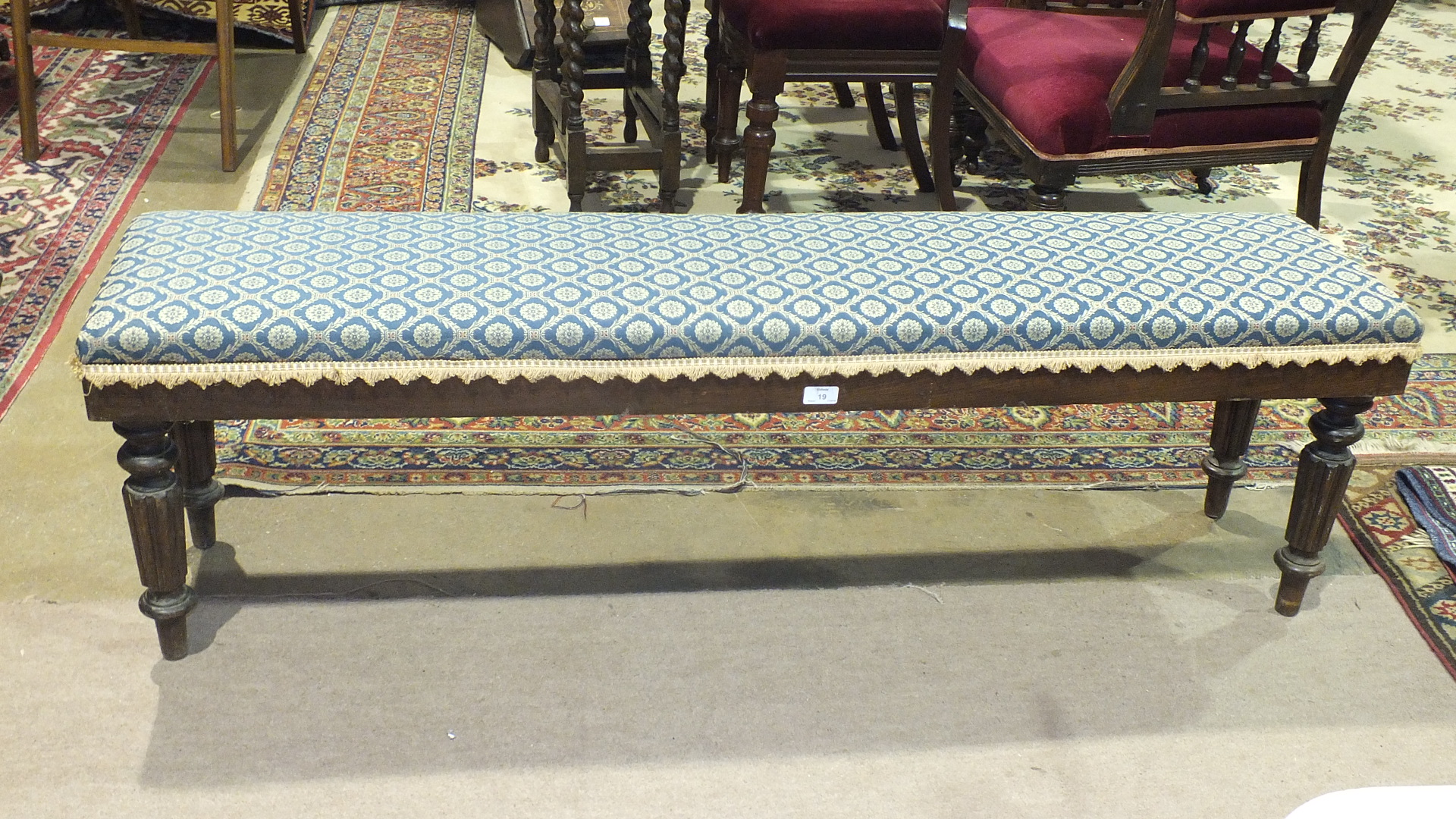 An upholstered stained wood window seat in the Victorian taste on fluted and turned legs, 151cm