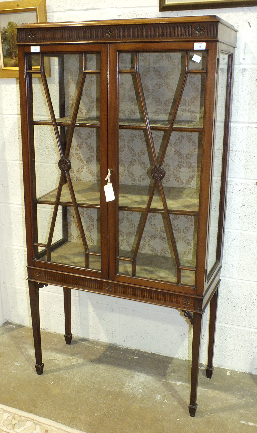 An Edwardian mahogany display cabinet, the rectangular top above a pair of glazed doors and glazed