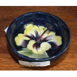 A small Moorcroft pin dish decorated in the Hibiscus pattern, 8cm diameter, with paper label and