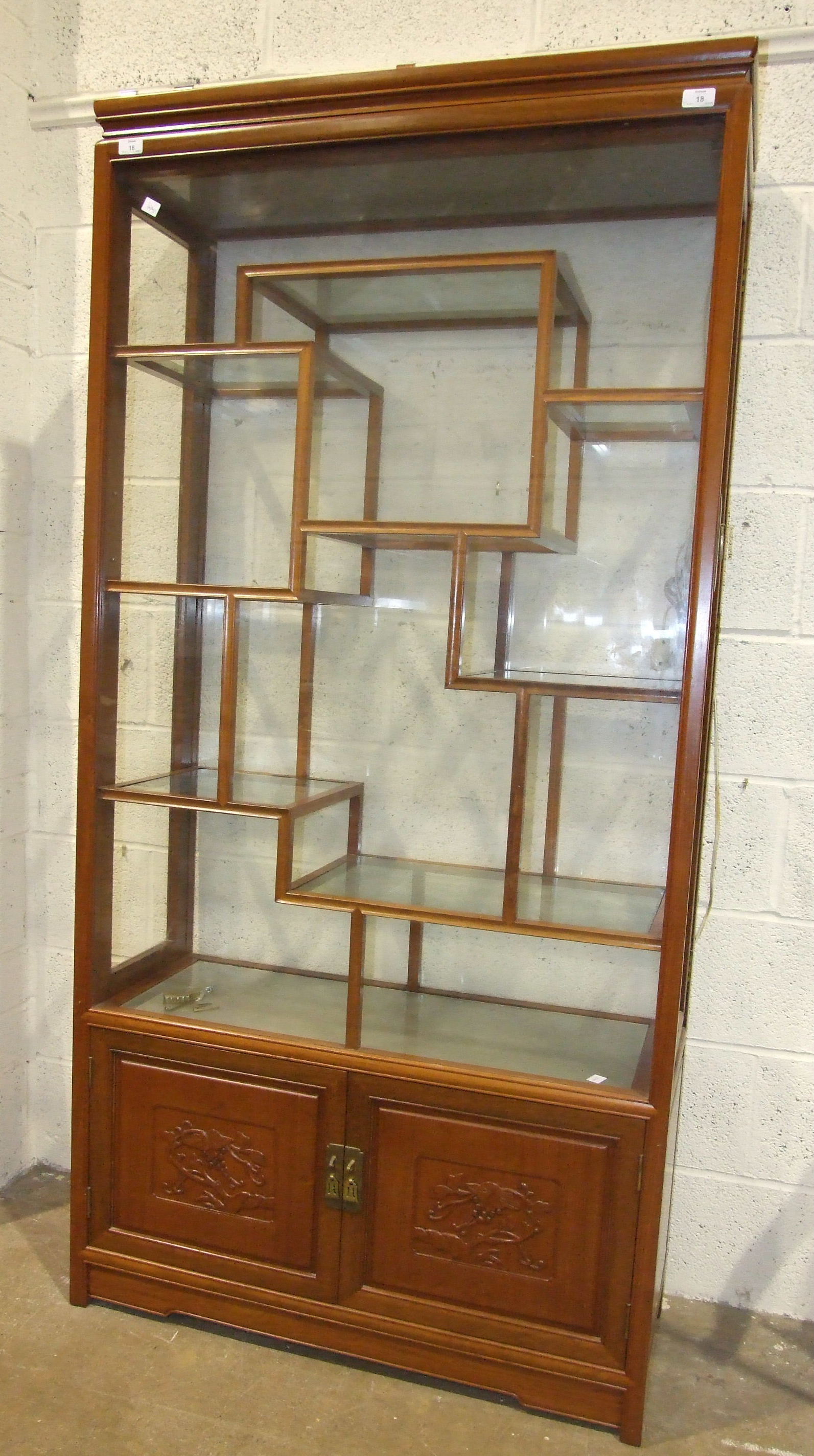 A 20th century Chinese-style hardwood and glazed display cabinet fitted with hinged side doors,