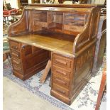An early-20th century oak roll-top desk, the interior fitted with drawer and pigeon holes over a