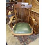 An early-20th century oak office swivel armchair with slatted back and padded seat and quadruped