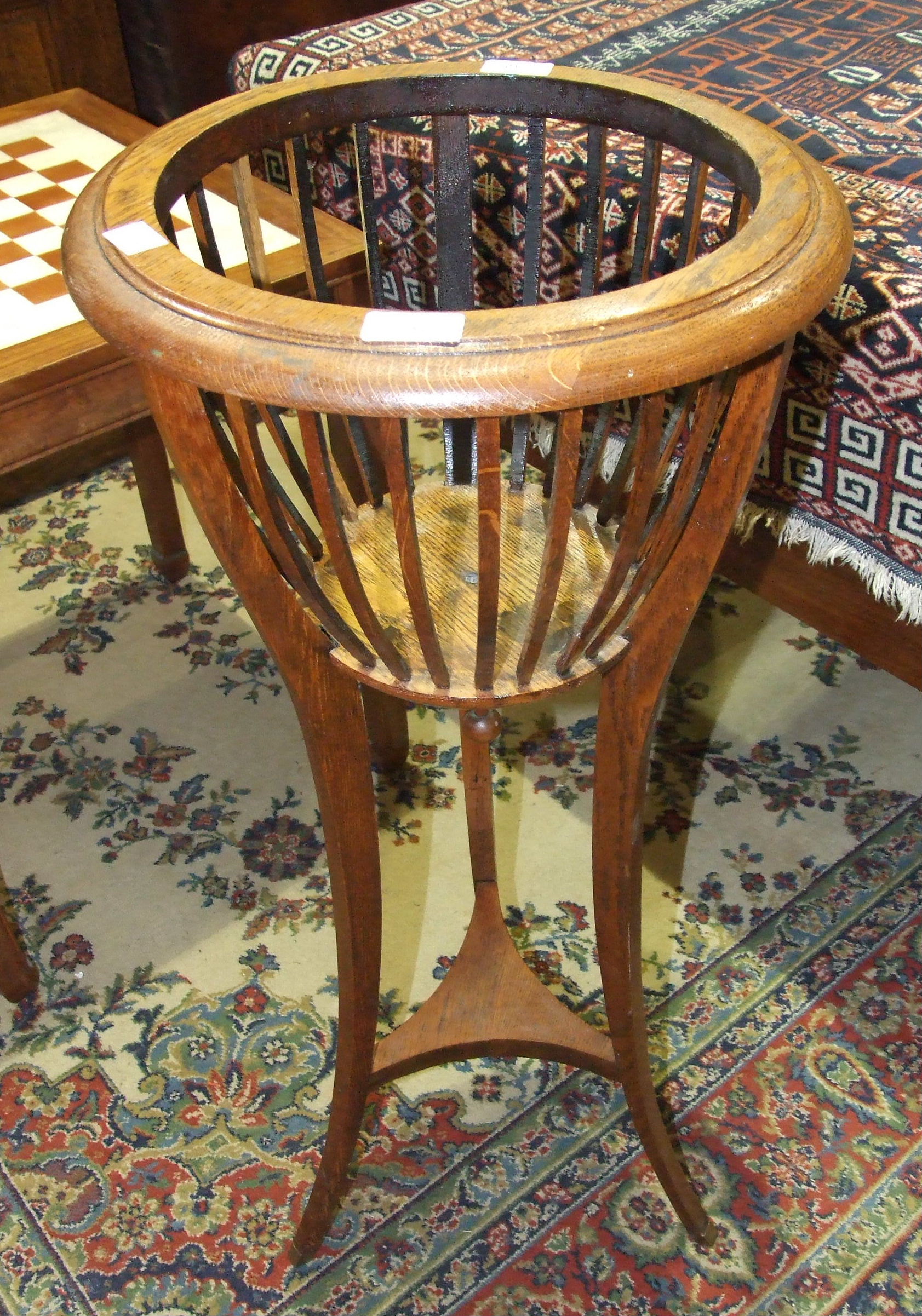 An Edwardian oak basket jardinière stand on three splayed supports united by an undertier, 37cm