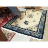 A large modern Chinese rug with deep blue borders on a camel-coloured ground, 279 x 184 and a