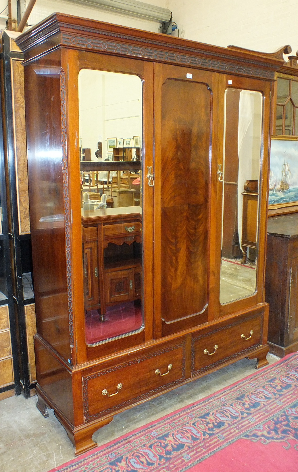 An Edwardian mahogany wardrobe, the cornice above a pair of mirrored doors, on a two-drawer base,