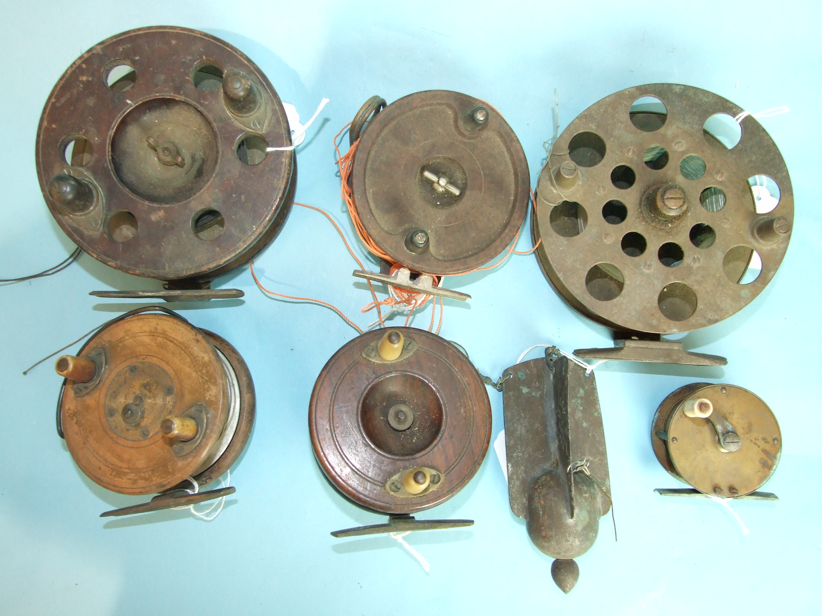 Three 19th century wooden trolling reels, an Alcocks Bakelite reel, a 19th century brass winch and