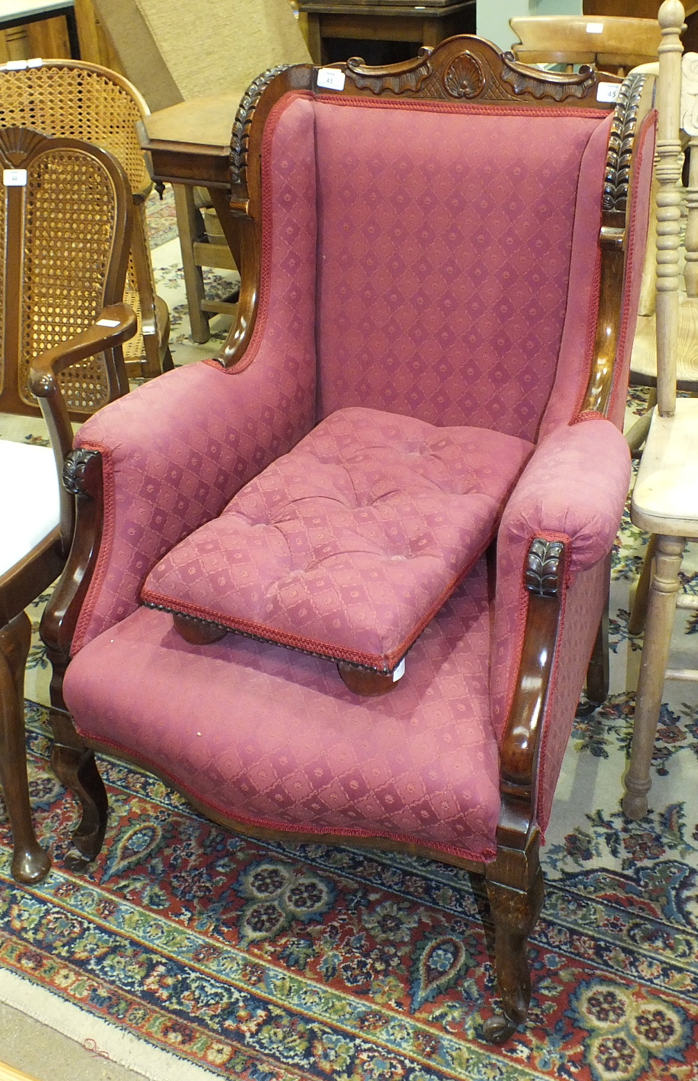 An upholstered armchair with stained wood frame, in the Victorian taste.