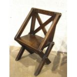 An antique oak X-framed chair, the top rail later carved with cross and symbols, 65cm high.