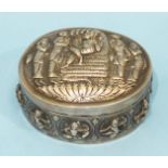 An Indian silver oval box with overall embossed figure decoration, 9cm diameter.