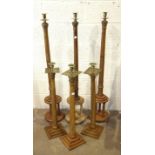 A set of three tall Masonic oak candle holders with brass sconces, on open circular bases, 130cm